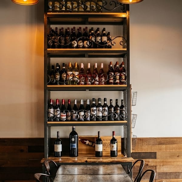 Tall metal wine rack filled with various bottles of red and white wine in a restaurant.