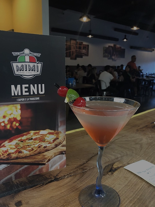 An image of Mimi's Menu standing up with a cocktail near by.